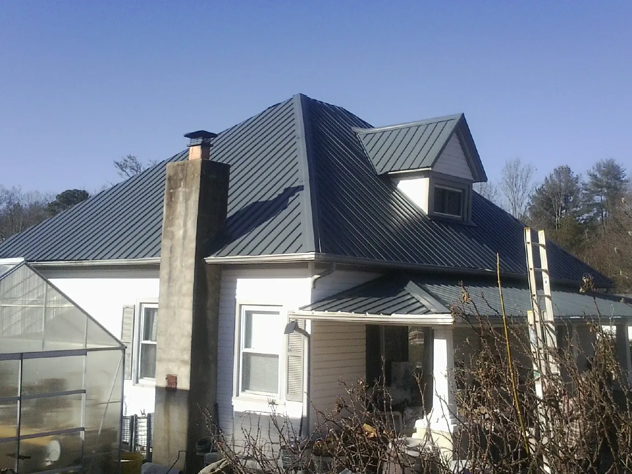 Dark blue standing seam metal roof on a white farmhouse with dormer — Slate & Tile Roof Repair by Roofing Brothers in Bonne Terre