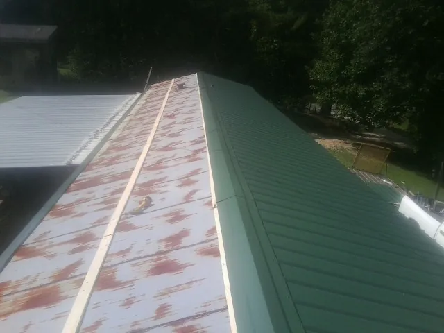 Old rusted panels beside newly installed green metal roofing — Wind Damage Roof Repair by Roofing Brothers in Bonne Terre