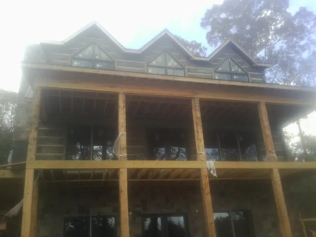 Dormers and porch framing on a large log home under construction — Roof Coating work by our crew in Bonne Terre