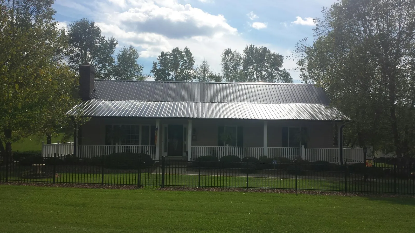 Gray metal roof on a brick ranch with a full width front porch — Gutter Guard Installation work by our crew in Bonne Terre