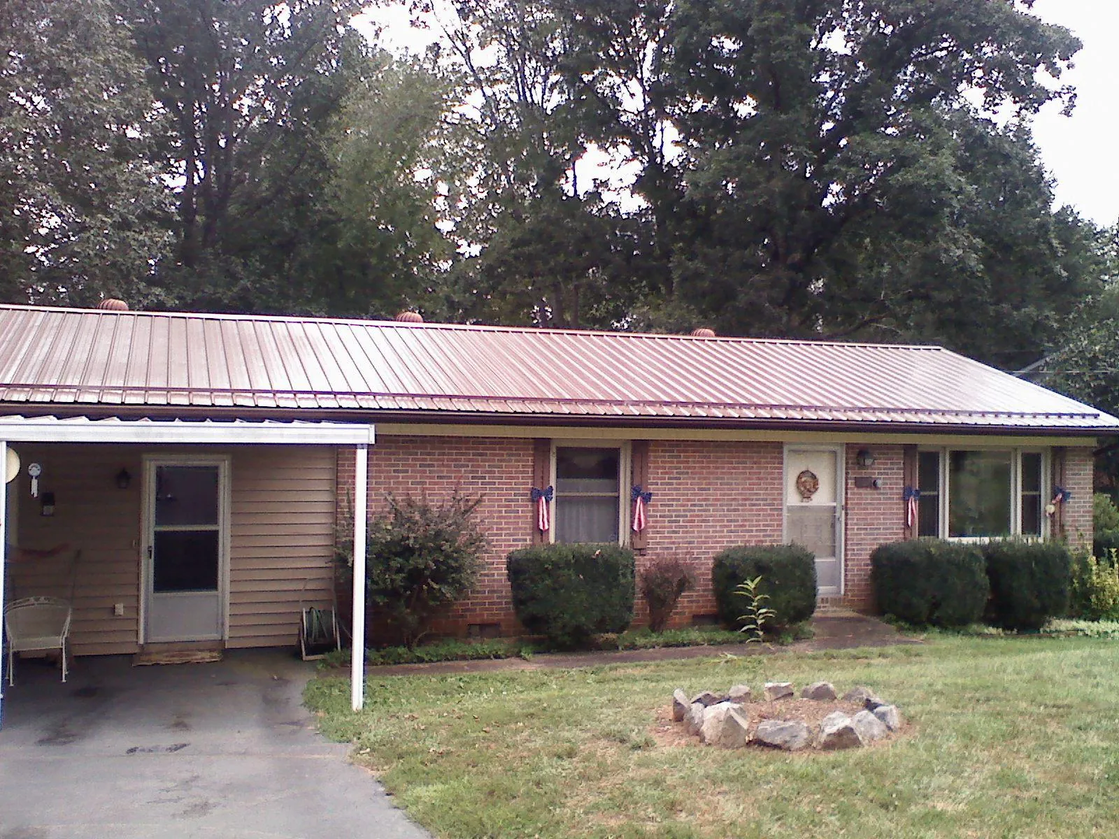 Bronze metal roof and carport on a brick ranch home — Roof Repair work by our crew in Bonne Terre